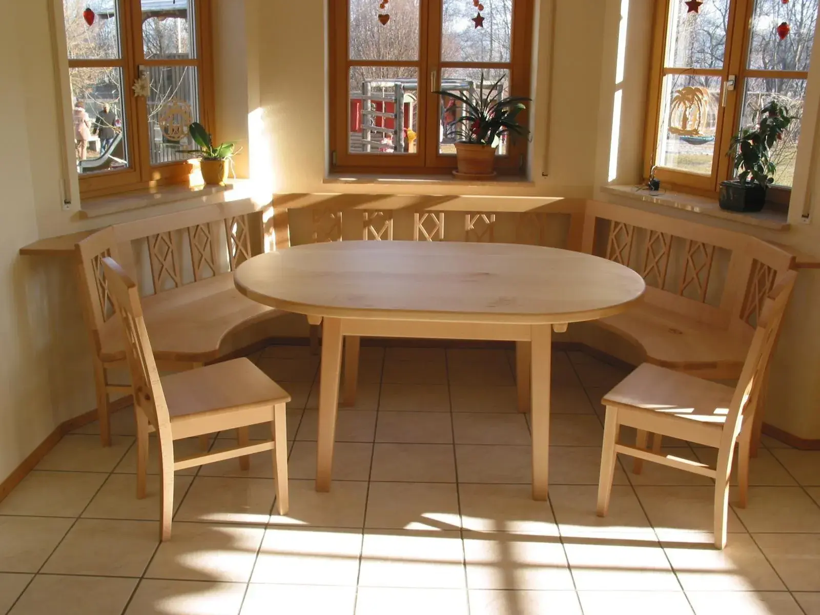 runde Bank mit Tisch und Stühlen in hellem Holz